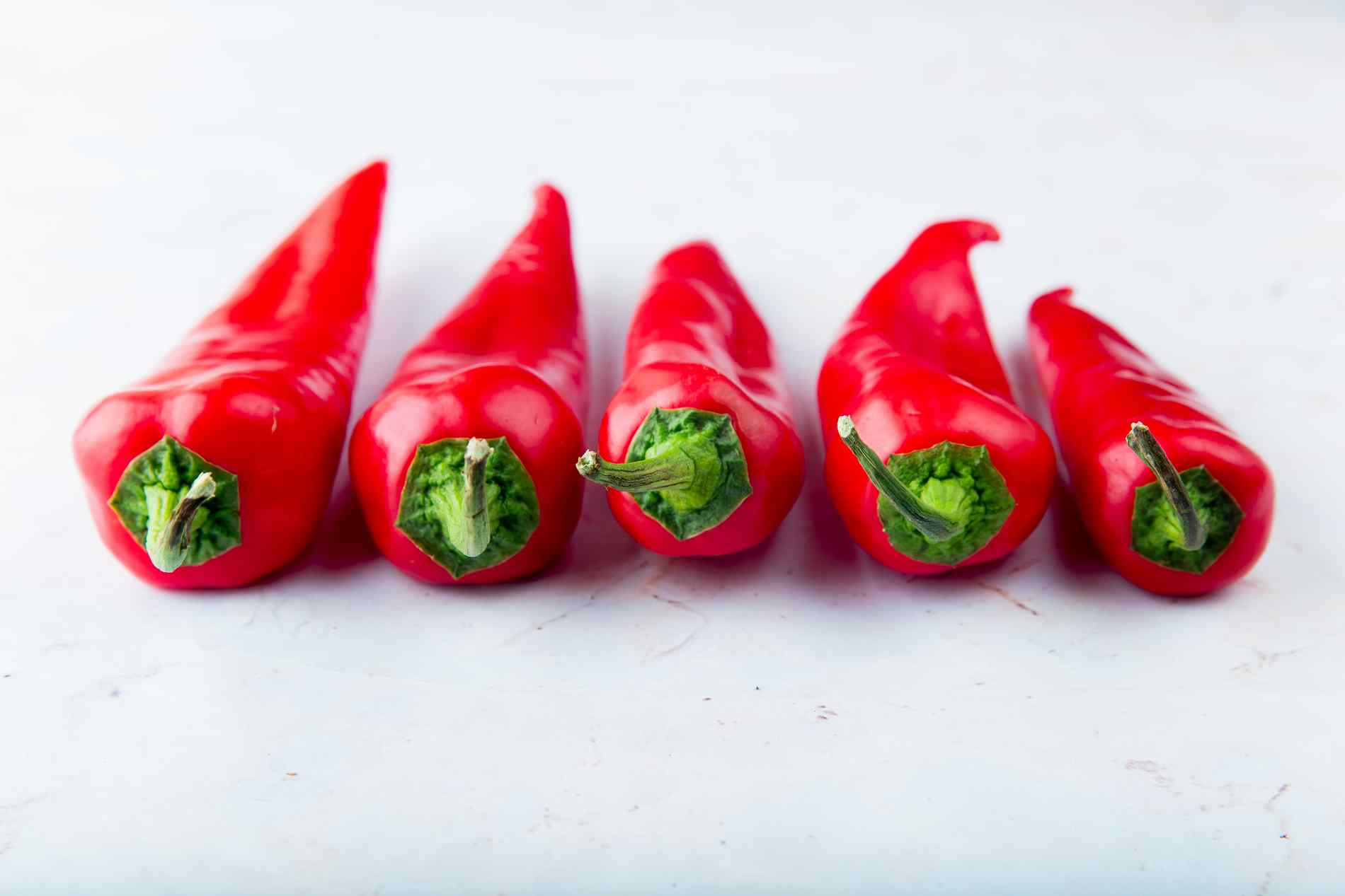 close up view of red peppers on white background with copy space
